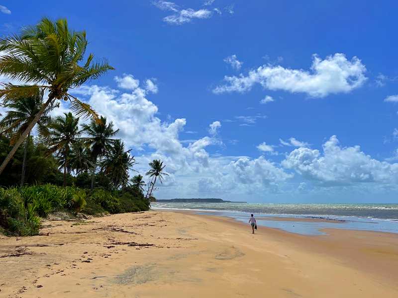 Homem caminha em praia de Caraíva