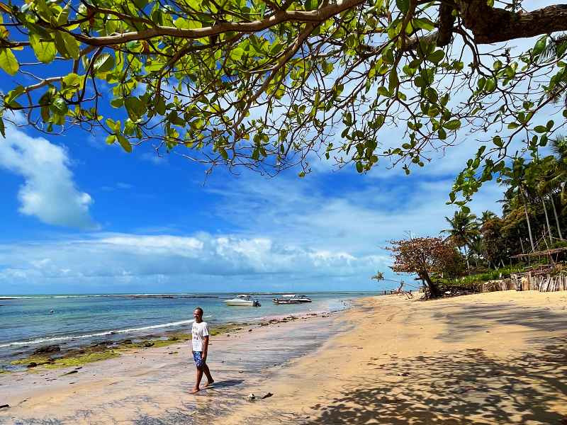 Homem caminha à beira-mar na maré baixa