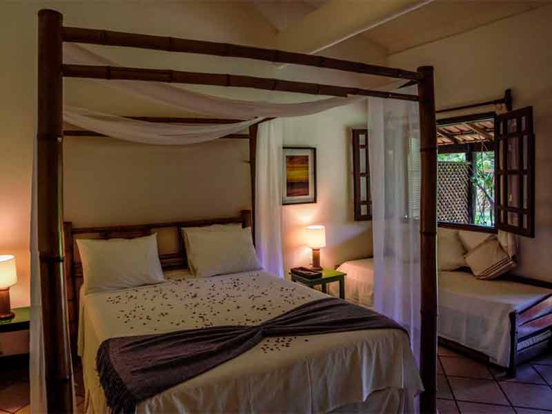 Quarto da Villa Cumuru, dica entre as pousadas em Cumuruxatiba, com cama de casal, mosqueteiro e cama de solteiro