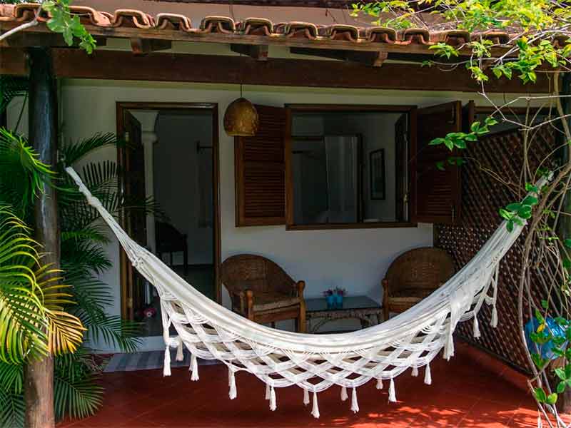 Entrada do quarto da Villa Cumuru com rede e cadeiras na varanda
