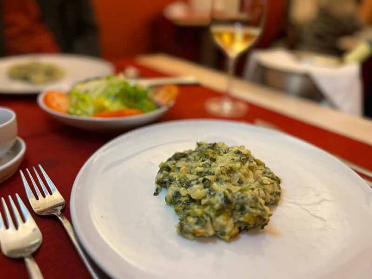 Bacalhau gratinado com espinafre com vinho e salada ao fundo no Café Alentejo, dica entre os restaurantes em Évora