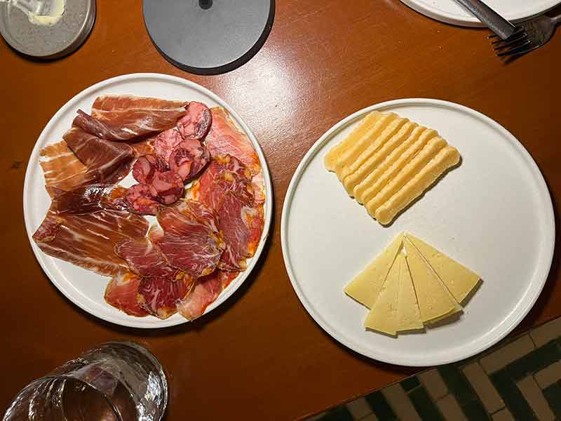 Queijos e carnes curadas em mesa do Cavalariça, dica entre os restaurantes no Alentejo