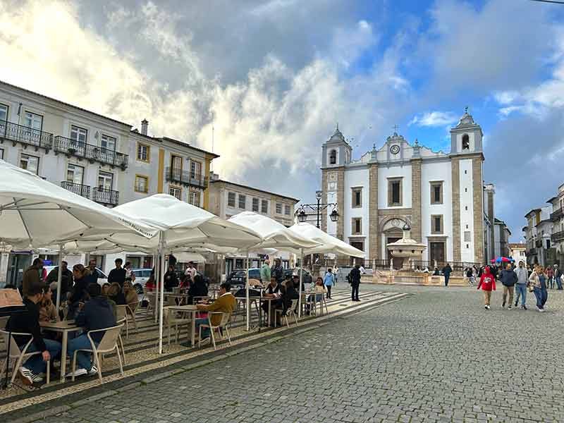 Igreja e mesas de restaurante na rua da Praça do Giraldo, em Évora