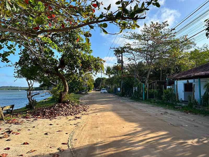 Rua principal de Santo André na Bahia com chão de terra, árvores e casas