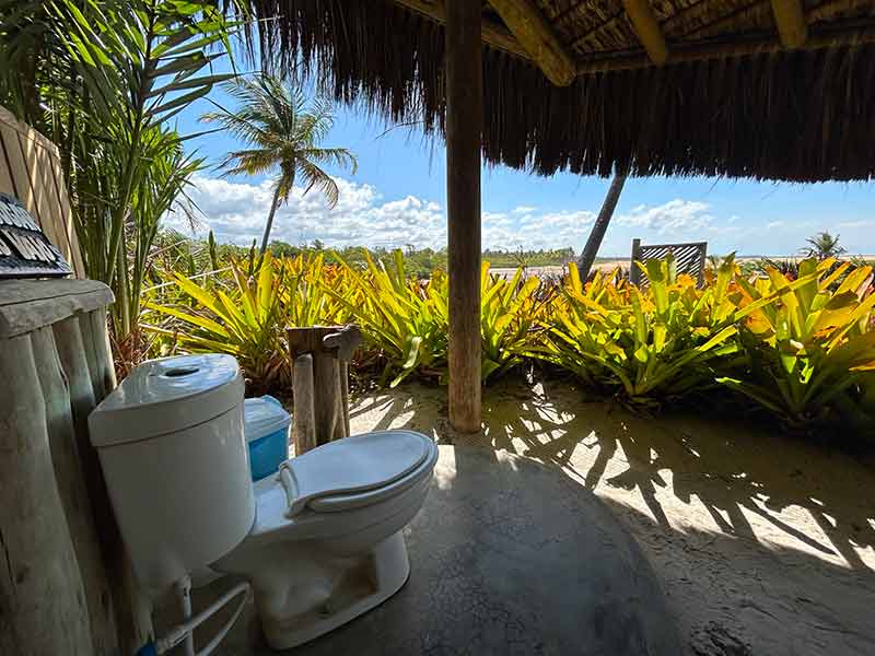Banheiro do restaurante Maria Nilza ao ar livre com vista para o mar e jardim