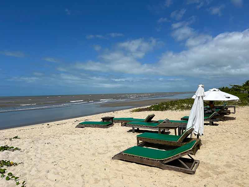 Espreguiçadeiras vazias na praia de Santo Antônio na Bahia em dia de céu azul com poucas nuvens