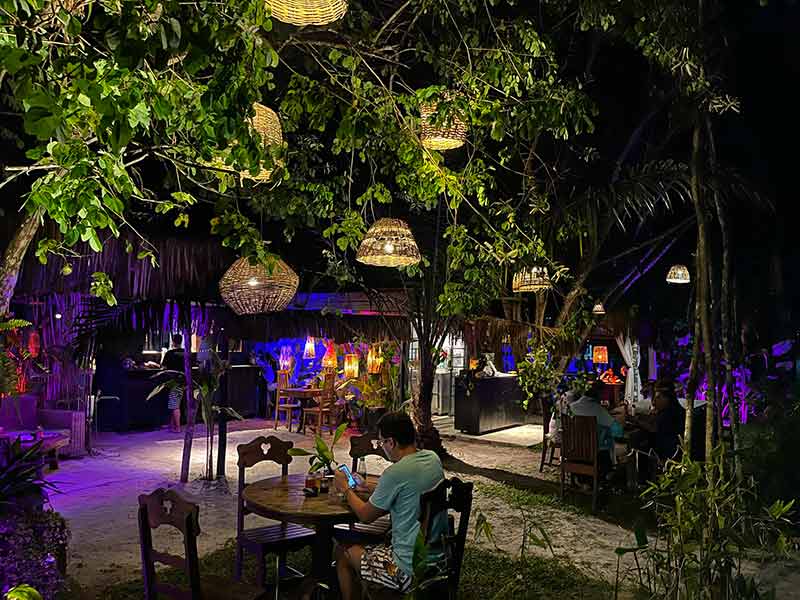 Gastrô Vila, um dos restaurantes da vila de Santo André, à noite com luminárias nas árvores e homem sentado à mesa