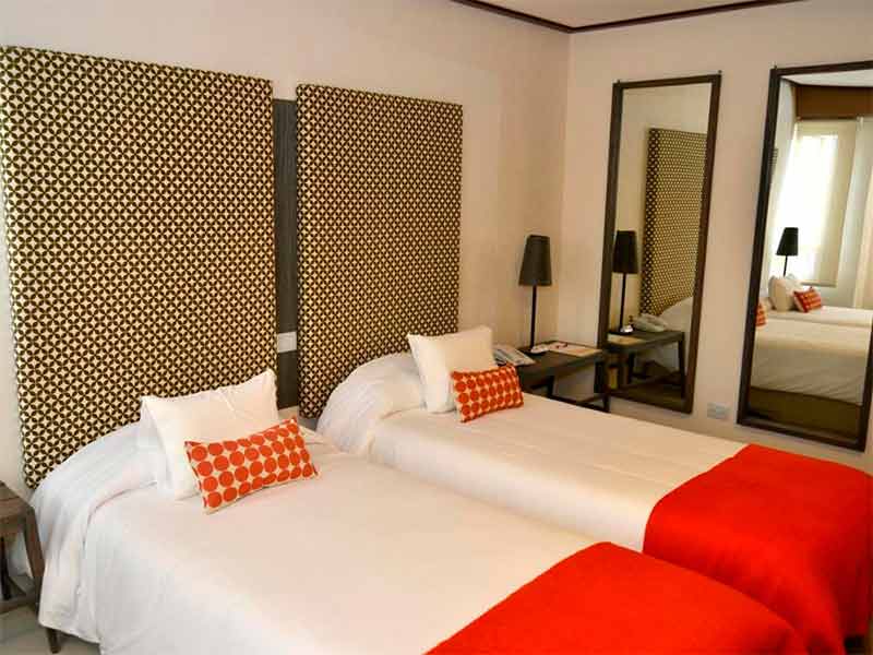 Hotel ACA El Calafate com duas camas de solteiro com roupas de cama em tons vermelhos
