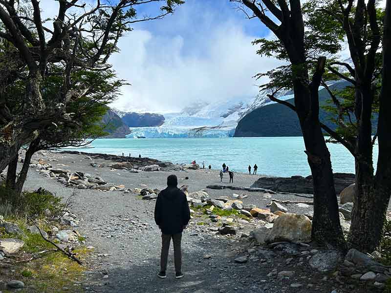 Homem caminha em praia com glaciar Spegazzini à frente, dica de o que fazer em El Calafate