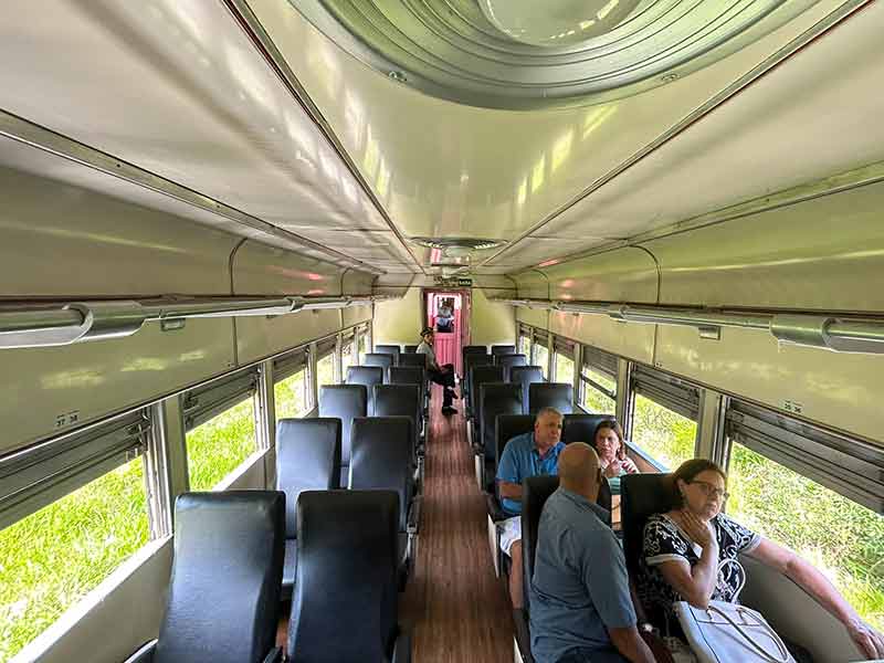Classe turística do trem de Guararema com poucas pessoas sentadas nos assentos