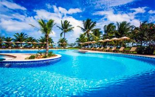 Piscina grande e vazia do Vila Angatu, dica de onde ficar em Santo André na Bahia, em dia de céu azul com algumas nuvens