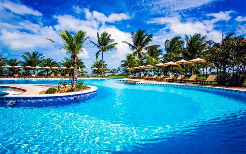 Piscina grande e vazia do Vila Angatu, dica de onde ficar em Santo André na Bahia, em dia de céu azul com algumas nuvens