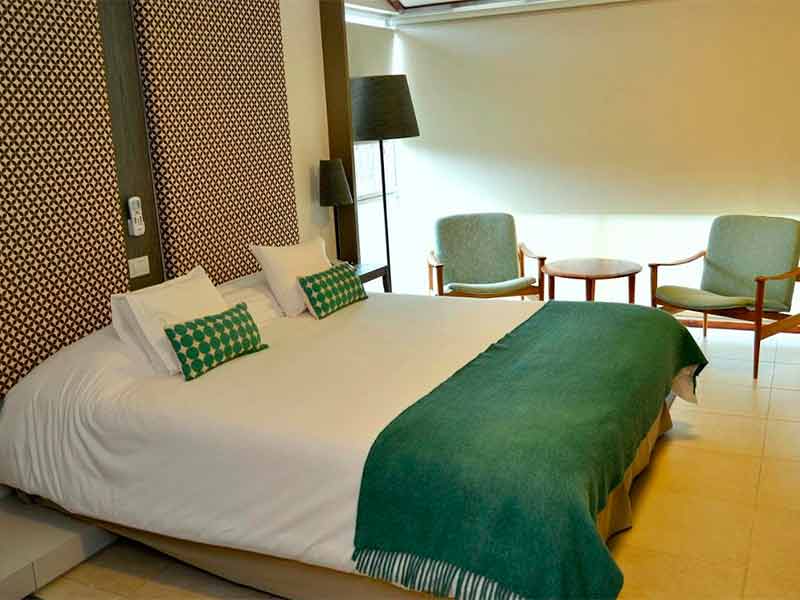 Quarto do ACA Hotel em El Calafate com cama de casal e roupa de cama verde
