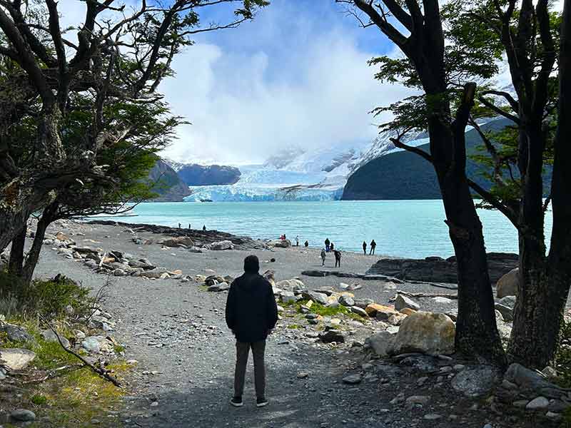 Homem em praia observa o Glaciar Spegazzini