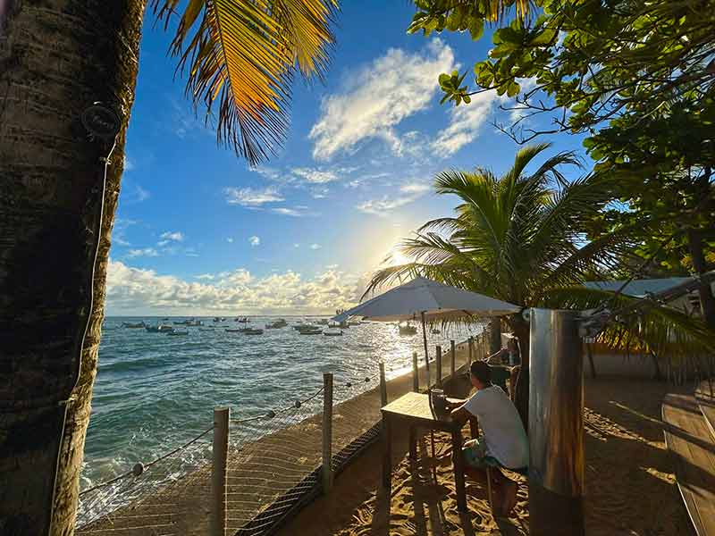 Homem sentado à mesa durante o pôr do sol no Restaurante Farol