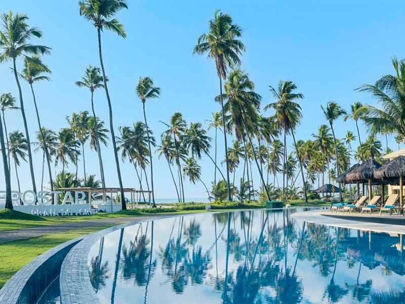 Área da piscina do Iberostar Selection Praia do FOrte com coqueiros em dia de céu azul