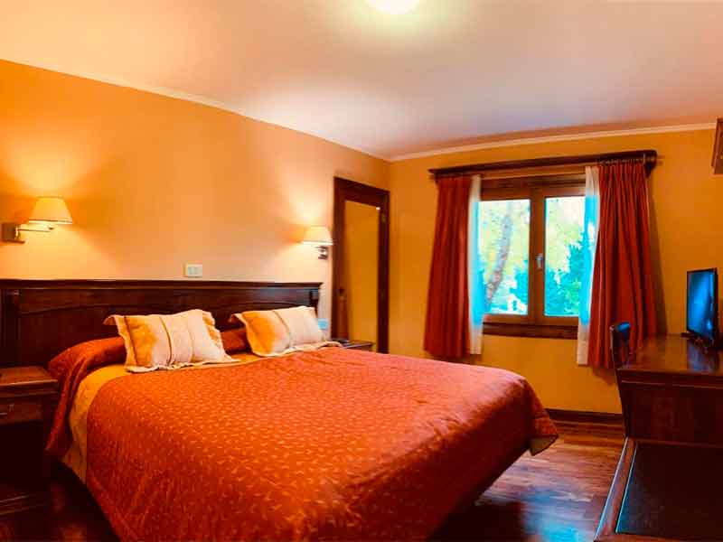Quarto do Patagonia Queen com cama de casal, piso de madeira e paredes amareladas