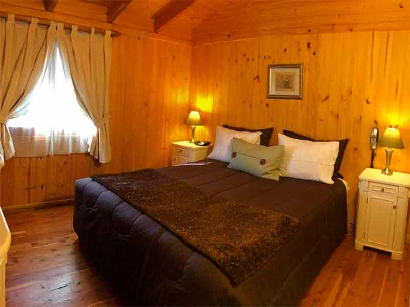 Quarto do Santa Monica Aparts com cama de casal e piso e paredes de madeira