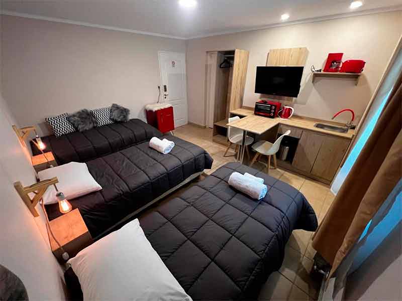 Quarto da Hosteria Yamile com três camas de solteiros, TV e frigobar