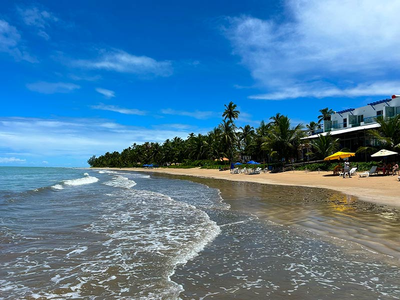 Mar vazio e alguns guarda-sóis na Praia do Bitingui, dica de o que fazer em Japaratinga, em dia de céu azul