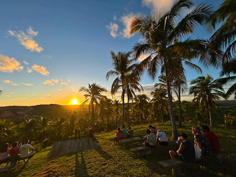 Pessoas assistem ao pôr do sol enquanto violinista toca no Paraíso Sunset, dica do que fazer em Japaratinga