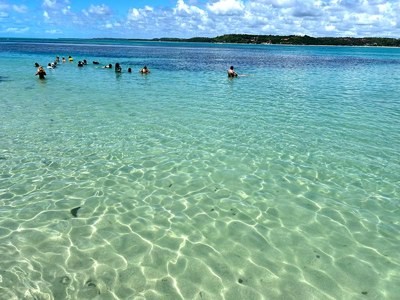 Pessoas aproveitam para relaxar nas piscinas naturais, dica de o que fazer em Japaratinga, em dia céu com poucas nuvens