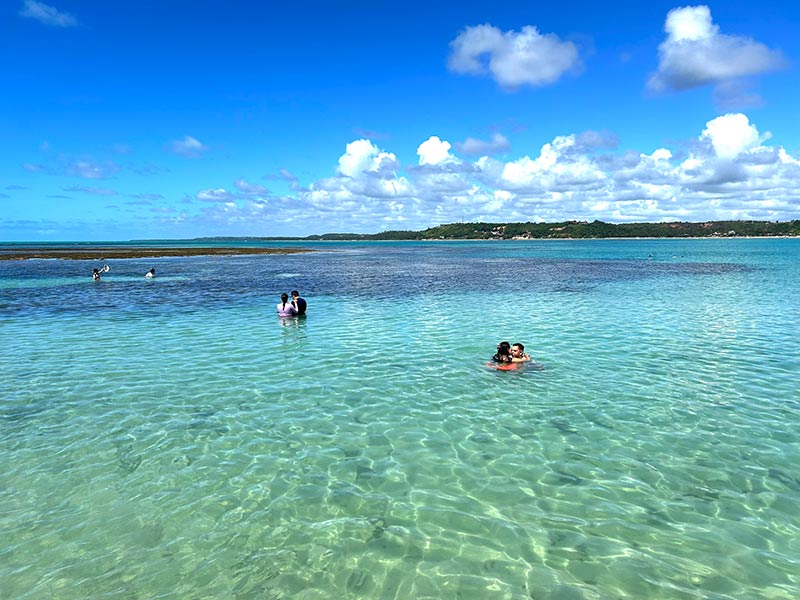 Pessoas aproveitam as piscinas naturais, dica de o que fazer em Japaratinga, em dia de poucas nuvens