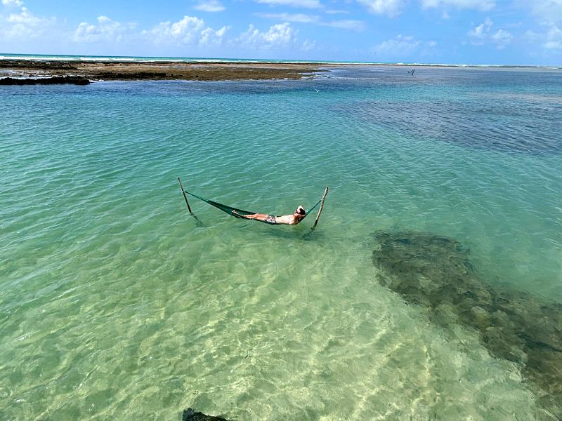Homem deitado em rede em piscina natural da Rota Ecológica de Milagres, em Alagoas