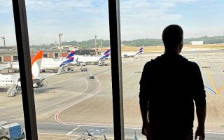 Homem de costas observa aviões no pátio do Aeroporto de Guarulhos