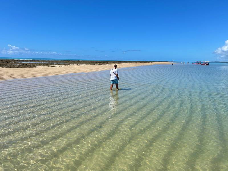 Homem caminha nas águas cristalinas da Croa de São Bento em Maragogi, Alagoas