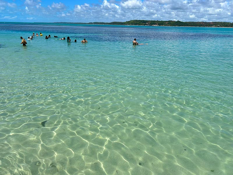 Pessoas nadam nas águas cristalinas das Piscinas Naturais de Japaratinga, em Alagoas