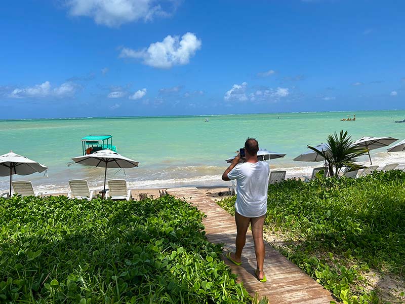 Homem tira foto do mar esverdeado na Praia de Lages, uma das melhores praias de Alagoas, na Pousada Rota Ecológica