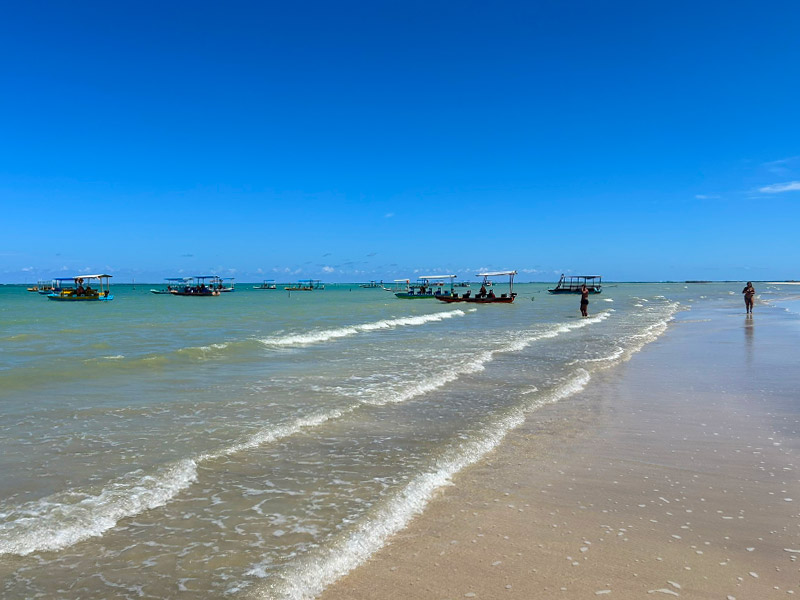 Pessoas e barcos no mar da Praia do Marceneiro, em Alagoas