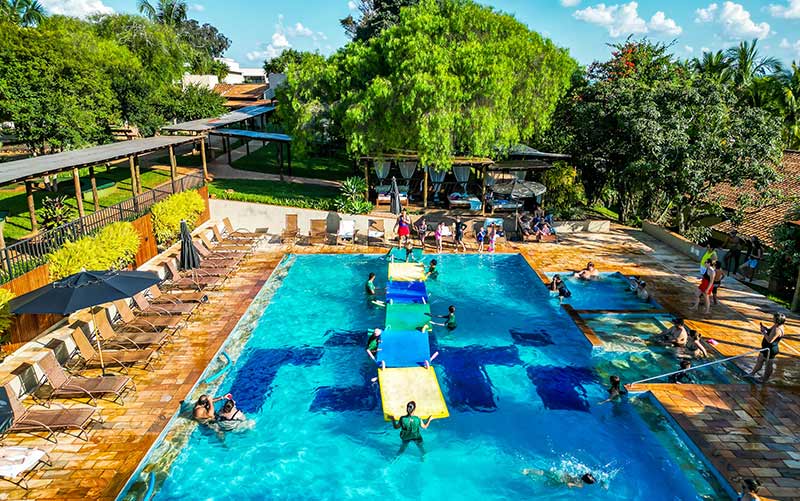 Hóspedes se divertem em piscina em dia de céu azul no hotel fazenda Areia que Canta