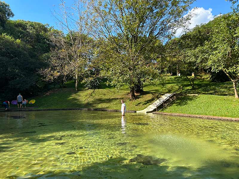 Homem em pé dentro de piscina natural no hotel fazenda Areia que Canta