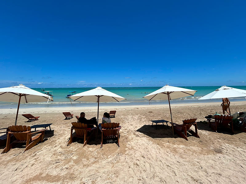 Pessoas em guarda-sóis e espreguiçadeiras no Mi Casa, na Praia do Riacho