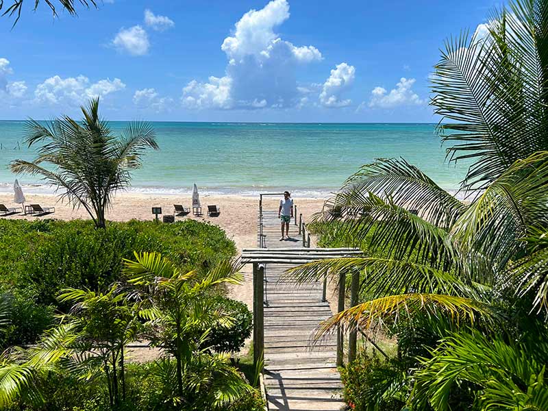 Homem caminha na passarela que dá acesso à Praia do Toque, uma das melhores praias de Alagoas, na Pousada Wassu
