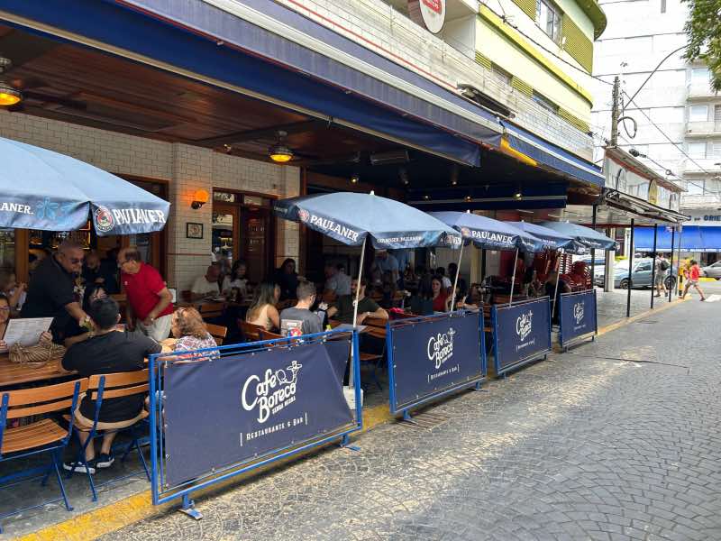Pessoas sentadas comendo e bebendo no Café Boteco