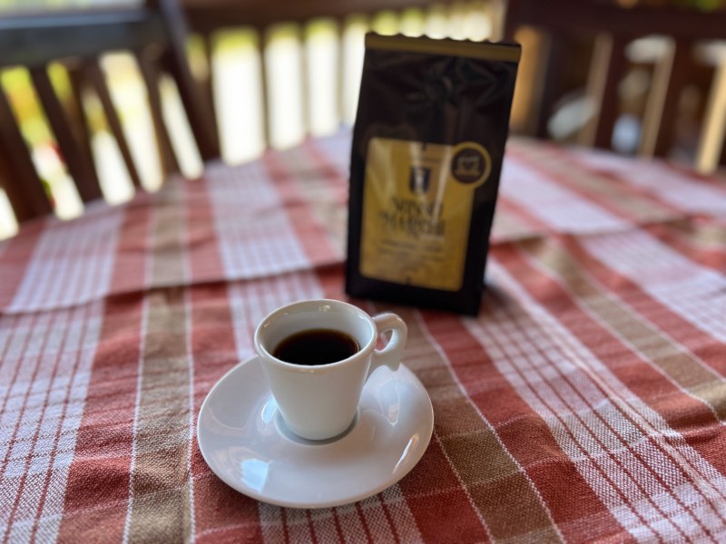 Xícara com o café Nonno Marchi, dica de o que fazer em Serra Negra, em mesa com toalha avermelhada