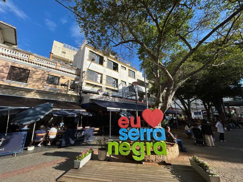 Praça João Zelante, dica de o que fazer em Serra Negra, com letreiro da cidade em dia de céu azul