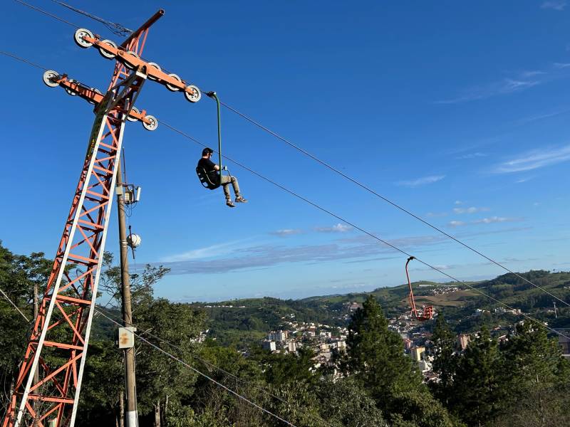 Homem desce em teleférico sozinho em dia de céu azul sem nuvens