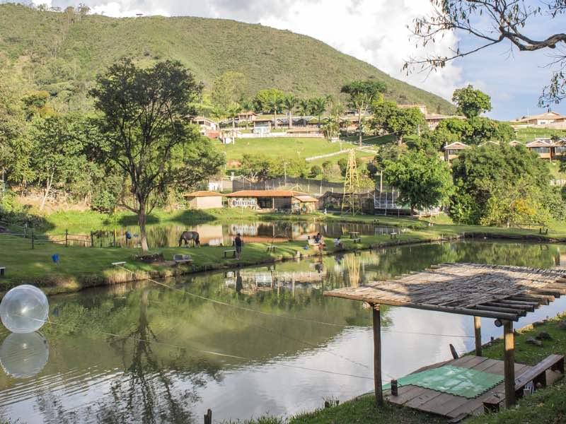 Área externa da Fazenda Morro Pelado, dica de o que fazer em Águas de Lindoia, com árvores, lago e casinhas