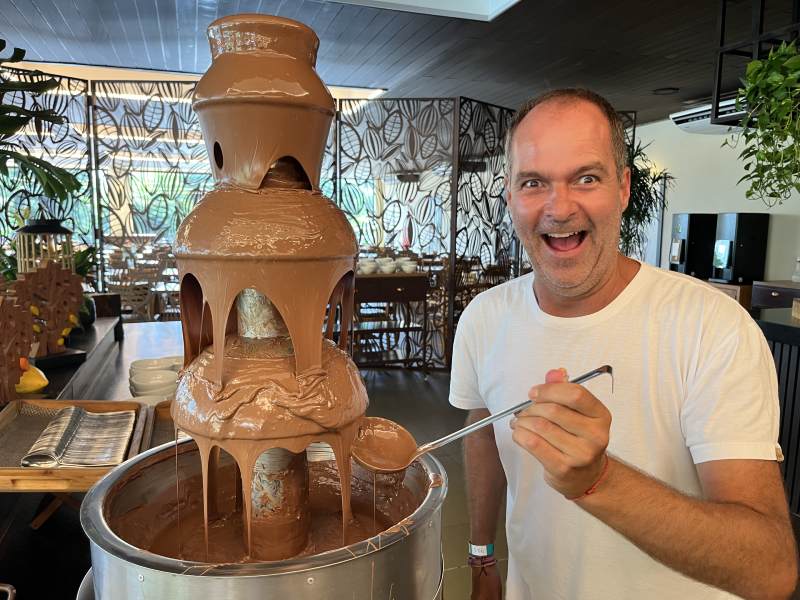Homem do lado da cascata de chocolate derretido no Bendito Cacao Family Resort
