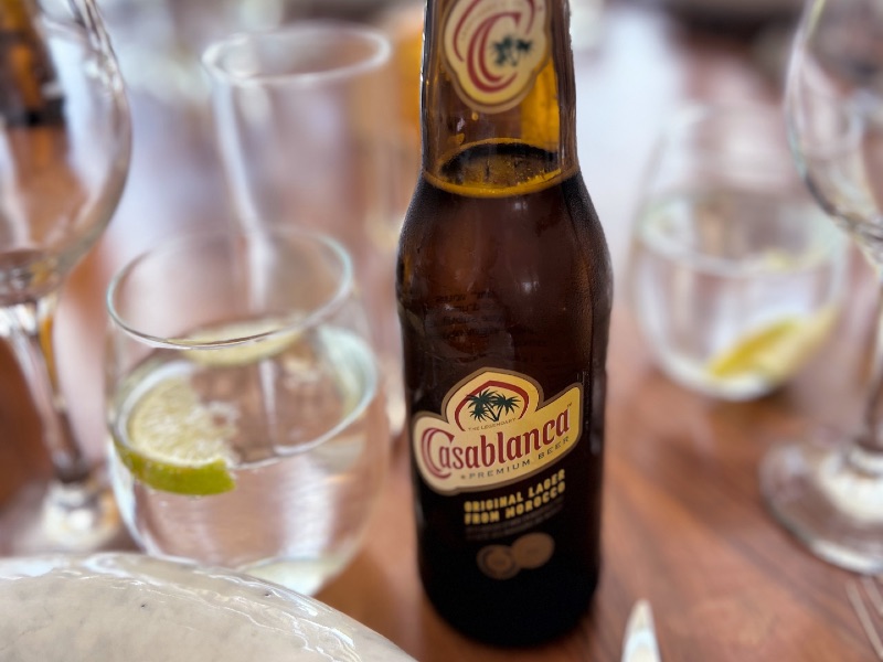 Garrafa pequena da Cerveja Casablanca, a mais famosa do Marrocos, em mesa com copos com água e limão