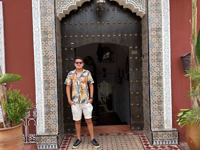 Homem posa em frente à porta com arquitetura marroquina