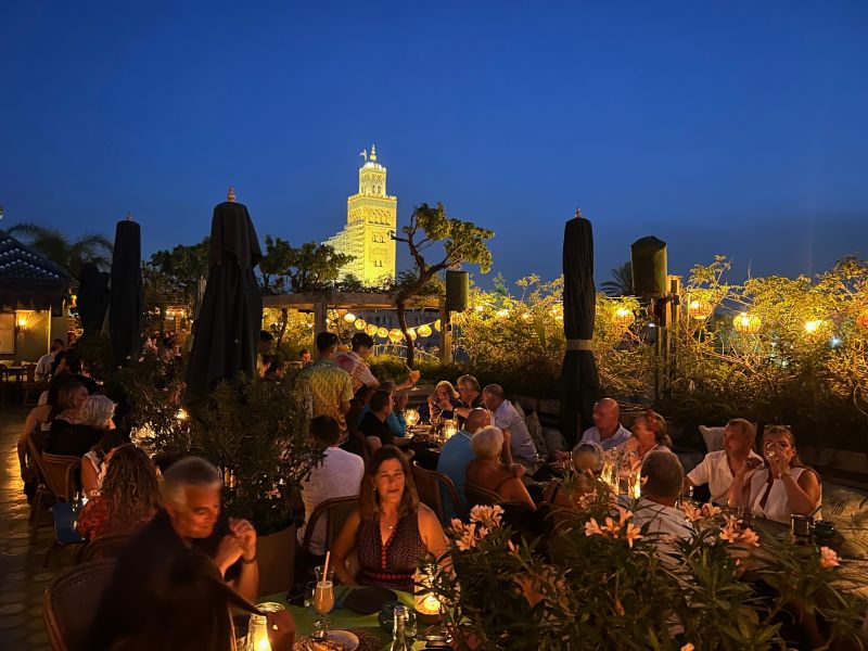 Pessoas comendo e bebendo no Kabana Rooftop, dica de onde comer em Marrakech, com vista para a Mesquita Koutoubia