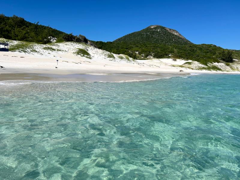 Água cristalina da Praia do Farol em dia de céu azul em Arraial do Cabo