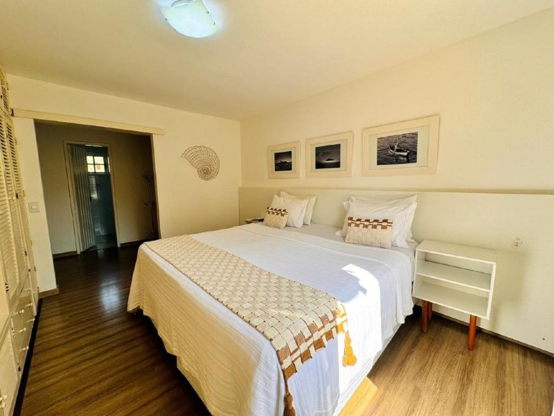 Quarto do Arraial Inn, dica de onde ficar em Arraial do Cabo, com cama de casal, quadros na parede e piso de madeira