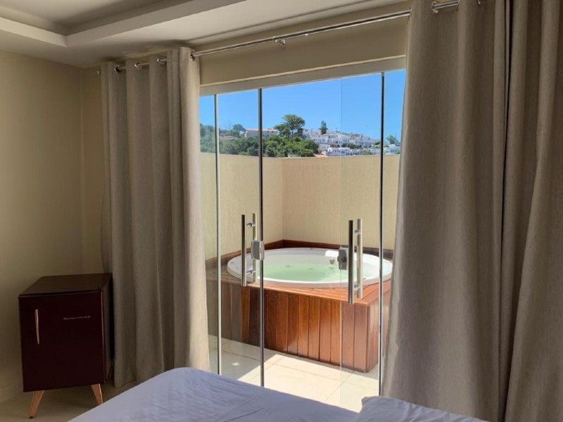 Banheira de hidromassagem em área externa de quarto da Arraial Tropical, dica de onde ficar em Arraial do Cabo, com cama e frigobar