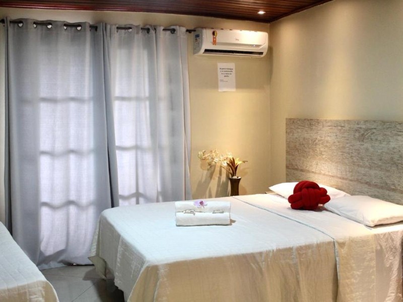 Quarto da Pousada dos Atobás, dica de onde ficar em Arraial do Cabo, com cama de casal, ar-condicionado e cortinas fechadas